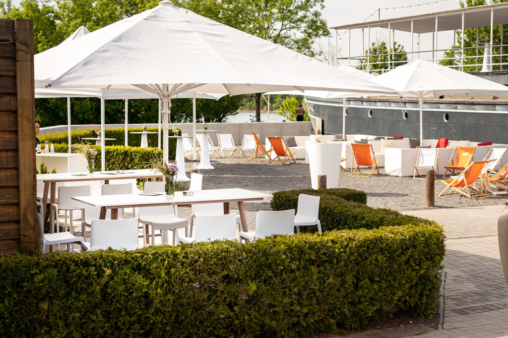 Außenbereich der amSee Location Leipzig, eingerichtet mit Sonnenschirmen und Loungemobiliar.