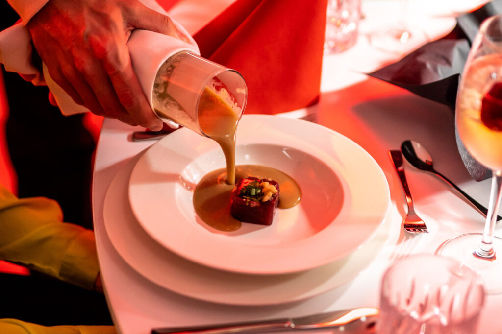 Einsetzen einer Suppe am Platz - Teller mit vorbereitetem Gelée, in den gerade Suppe gegossen wird.