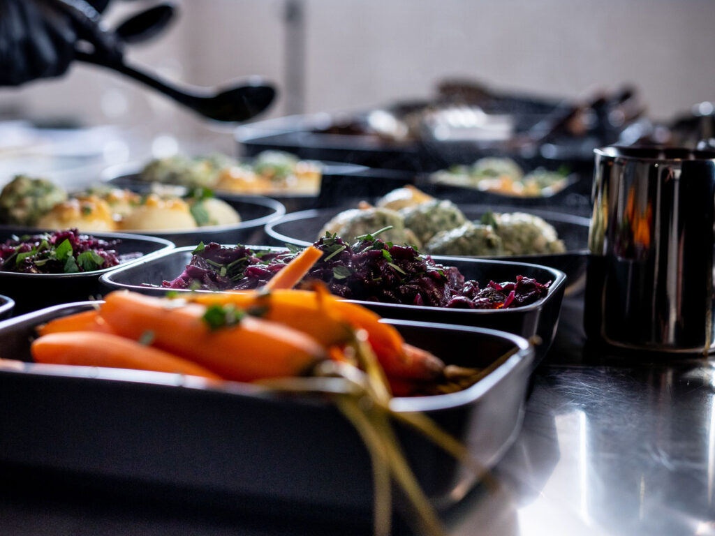 frisch gekochte Möhren, Rotkohl, Knödel in grauen Servierschalen